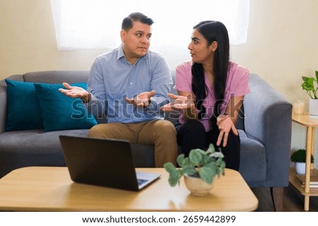 Latin couple gesturing while explaining their problems to psychologist during online therapy session using laptop at home