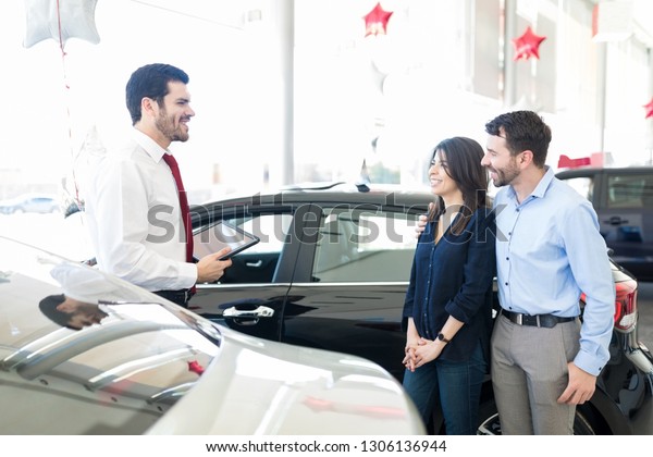 Latin couple having a informative discussion\
with salesperson before buying\
car
