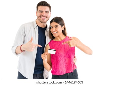 Latin Couple Smiling While Pointing At Credit Card Against White Background