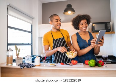 Latin couple using a digital tablet while cooking in kitchen. - Powered by Shutterstock