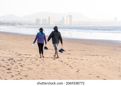 Latin Couple Walking Barefoot On The Beach In La Serena