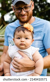 Latin Dad Man With His Baby Daughter On His Legs She Serious. Vertical Photo