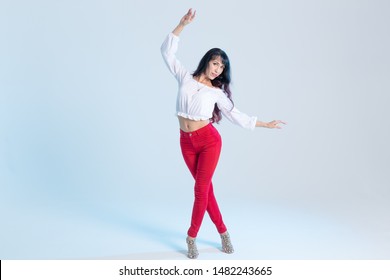 Latin Dance, Contemporary Dance, Bachata Solo And Cha-cha-cha Concept - Portrait Of A Young Woman Salsa Dancer In A Dance Pose On Blue Background With Copy Space