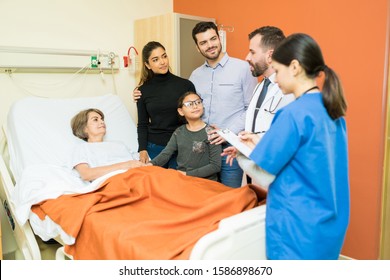 Latin Doctors Discussing With Senior Patient And Her Family At Hospital During Visit