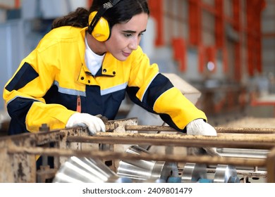 Latin engineer in safety uniform work in heavy steel engineering factory. Young female hispanic worker wear protective gear checking production machinery equipment in metalwork manufacturing facility - Powered by Shutterstock