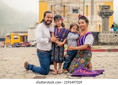 Latin Family Smiling Looking At The Camera With Their Two Children.
Hispanic Family In Front Of A Church In A Rural Area.