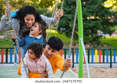 Latin family with two children playing together in a playground. Hispanic family. - Powered by Shutterstock