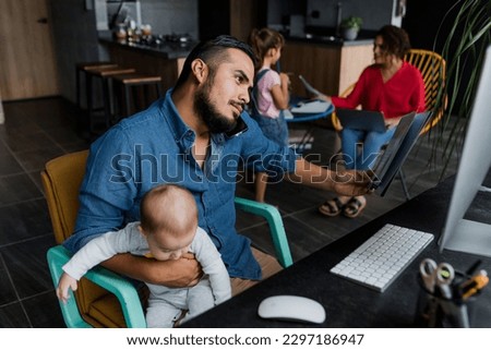 latin father using computer and working at home while he take care of his baby son in Mexico Latin America, home office concept, hispanic family