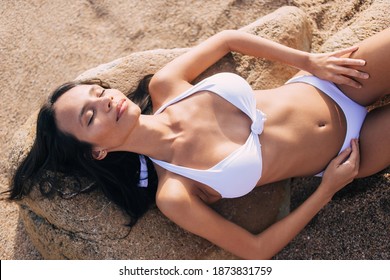 Latin Female Dressed In Swimwear Enjoying Bikini Season For Dreaming On Beach Lying On Oceania Stone, Perfect Woman 20 Years Old Sleeping While Sunbathing During Summer Vacations On Philippines