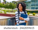 Latin female student smiling standing outside the campus of the university holding folder and carrying rucksack