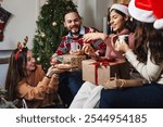 Latin friends holding gifts and sitting near Christmas tree at home in Mexico. Holidays and celebration in Latin America