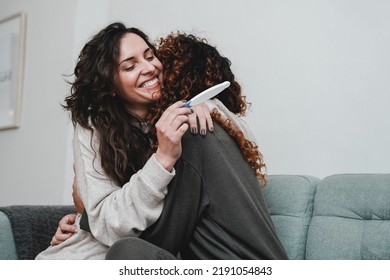 Latin Gay Female Couple Celebrating With Pregnancy Test At Home - Focus On Left Mother Face - Lgbt Lesbian Concept