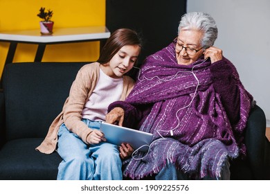 Latin Granddaughter Listening Music With Her Mexican Grandmother At Home In Mexico City