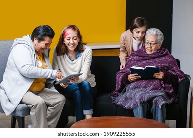 Latin Granddaughter And Mexican Grandmother Reading A Book And Tablet In Mexico City