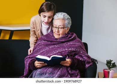 Latin granddaughter and mexican grandmother reading a book and tablet in Mexico city