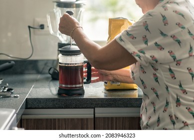 Latin Grandma Preparing Coffee With A French Press For Breakfast