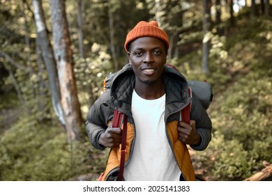 Latin guy wander among trees with backpack, young man enjoying time alone in forest. Escape from hectic life to wildlife. Camping, hiking, travelling, search for adventures concept