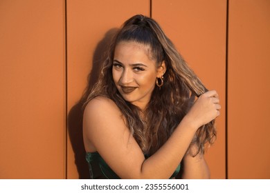 Latin and Hispanic girl, young and beautiful, with green eyes and big eyelashes, pulling her hair in a funny attitude. Concept beauty, fashion, gestures, hairstyles, curly.