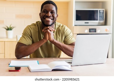 Latin Hispanic Man Looking Happy While Sitting With Laptop And Papers At Kitchen