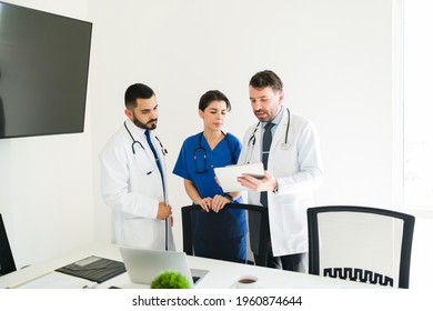 Latin Hospital Director Showing The Medical Information Of A Patient On A Tablet To A Young Doctor And Female Nurse At The Meeting Room