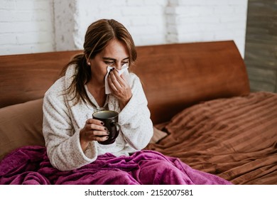 latin ill adult mature woman sneezing and using napkin for flu on bed at home in Mexico Latin America