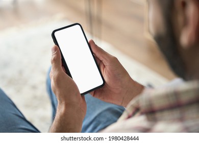 Latin Indian Adult Businessman Holding Using Mock Up Of Cell Mobile Smartphone With Empty Blank White Screen For Advertising. Over Shoulder Closeup View.