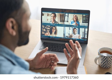 Latin indian businessman having virtual team meeting group call chatting with diverse people in customer support. Video conference call on computer with manager and employees. Over shoulder view. - Shutterstock ID 1979117360