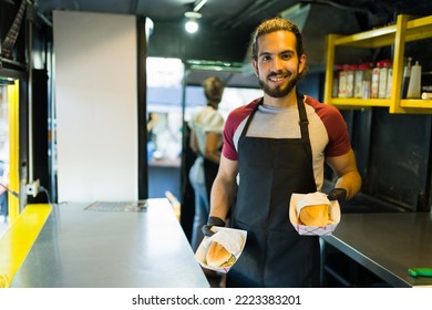 Latin male chef smiling looking happy while finishing preparing fast food at the food truck - Powered by Shutterstock