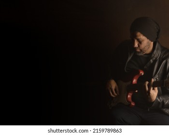 Latin Man Of 40 Years Old Playing Guitar With His Leather Jacket Dark Photo With Dark Background Musical Concept