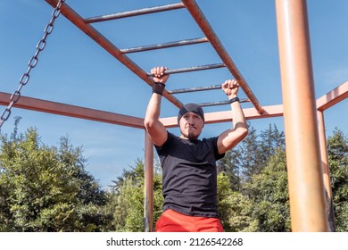 Latin Man Doing Arms Exercise Crossing The Brachiation Ladder Outdoors. Monkey Ladder Exercise