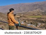 latin man dressed in a mustard-colored sweatshirt, drinking mate looking at the landscape from a balcony in tafi del Valle, Tucuman, Argentina. Relaxed vacation