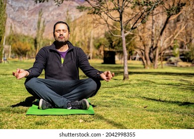 Latin Man Meditating In The Sunny Park