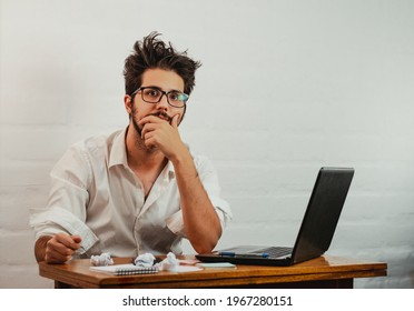 Latin Man In The Office, Gesturing Fatigue And Stress. Looking Straight Ahead Bored And Disheveled. Work At Home Concept. Copy Space.