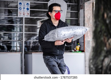 Latin Man Picking Up Clothes At The Local Dry Cleaning With Face Mask Due Coronavirus Protocols