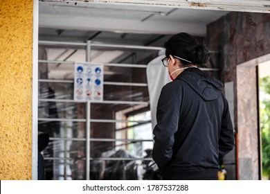 Latin Man Picking Up Clothes At The Local Dry Cleaning With Face Mask Due Coronavirus Protocols