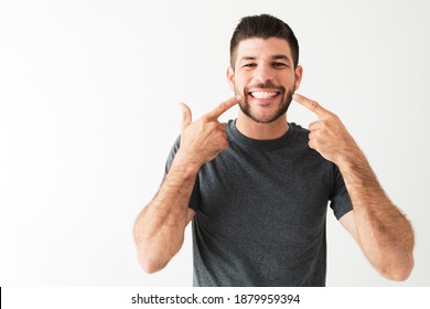 Latin Man Pointing To His Big And Bright Smile. Portrait Of A Handsome Man With White Teeth Is Smiling And Looking Very Happy 