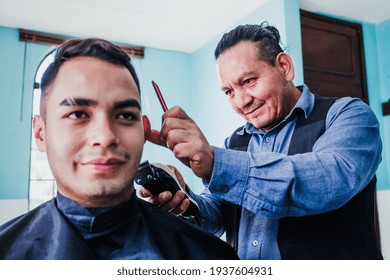 latin man stylist cutting hair to a client in a barber shop in Mexico - Powered by Shutterstock