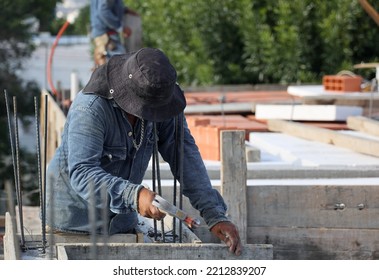 Latin Man With Sunhat Or Sombrero Preparing The Wood Formwork For The  Roof Using A Hammer And Nails. 