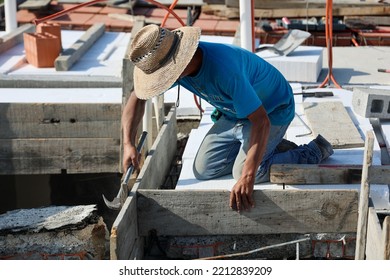 Latin Man With Sunhat Or Sombrero Preparing The Wood Formwork For The  Roof Using A Hammer And Nails. 