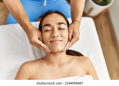 Latin Man And Woman Wearing Therapist Uniform Cleaning Skin Face At Beauty Center