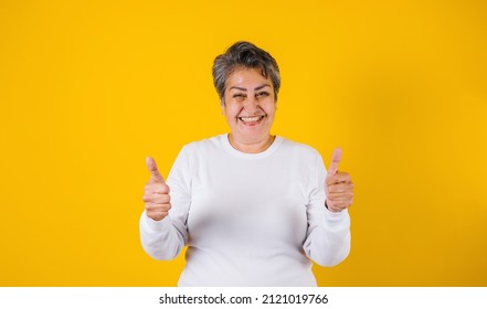 latin matured woman portrait with thumbs up on yellow background in Mexico Latin America - Shutterstock ID 2121019766