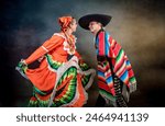Latin Mexican couple with Jalisco, charro costumes A man and woman in traditional Mexican clothing dance together. The man is wearing a sombrero and the woman is wearing a colorful dress. 