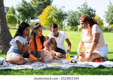 Latin multigenerational family having a picnic in a park - Powered by Shutterstock