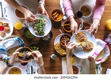 latin people eating Mexican food, grilled Tacos, spicy salsa, tortillas, beer, snacks and peoples hands over wood table in a restaurant terrace in Mexico Latin America