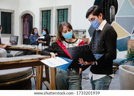 Latin people teamwork working in coworking while wearing face mask for social distancing in new normal situation preventing the infection of corona virus or covid-19, Mexican Coworkers in Mexico