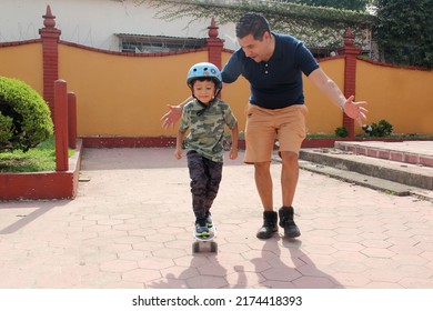 Latin Single Dad Teaches His Son To Ride A Skateboard With A Helmet Very Funny And Happy Of The Achievement Of Learning Something New
