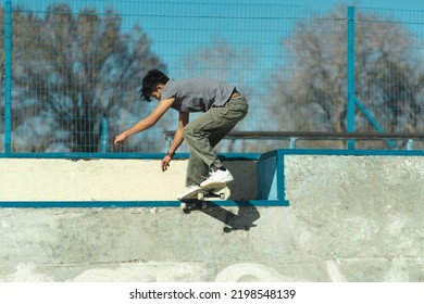 Latin Skater Boy Doing Trick In The Concrete Of Skatepark. Copy Space