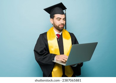 Latin smart college student using the laptop receiving his university degree after studying online and receiving his diploma - Powered by Shutterstock