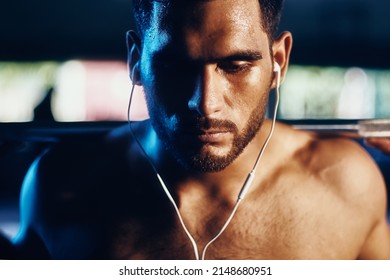 Latin strong man lifts weight in the gym listening to music with his headphones, very concentrated and motivated. - Powered by Shutterstock