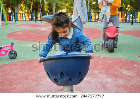 Latin three years old boy playing spinner bowl at a playground